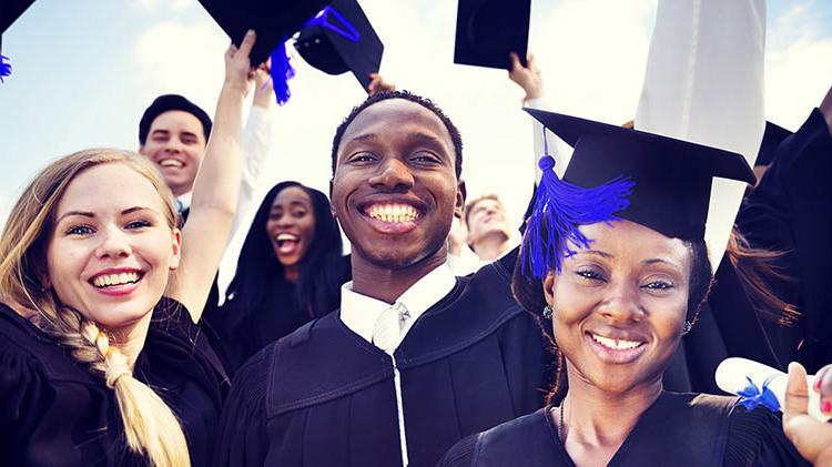 A group of young adults smiling after their college graduation ceremony.