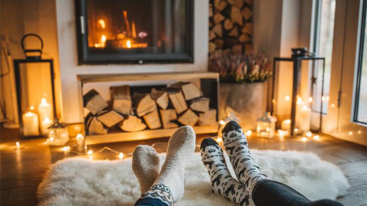A couple in socks sit and enjoy their fireplace.